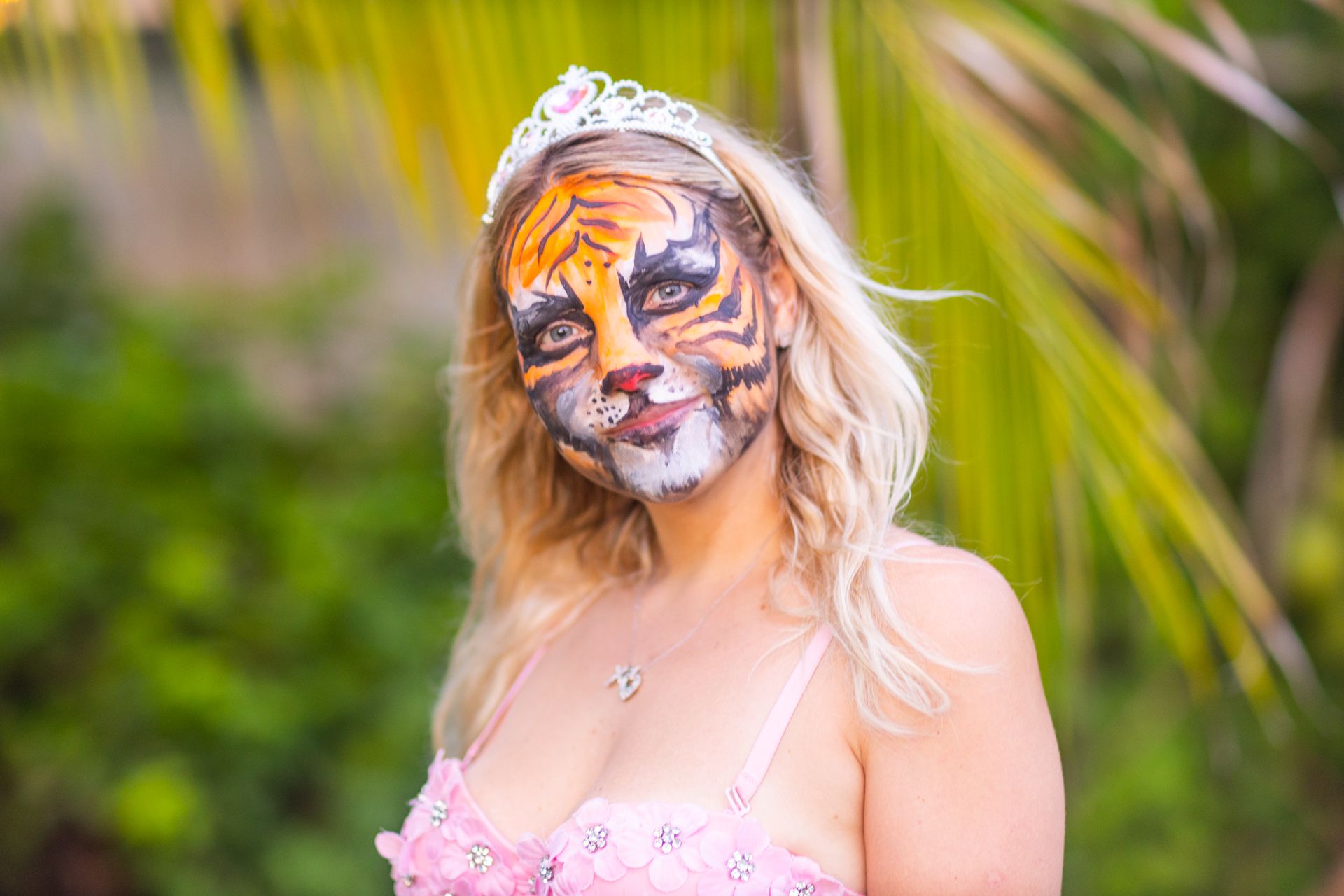 A girl in a tiara with a tiger painted on her face